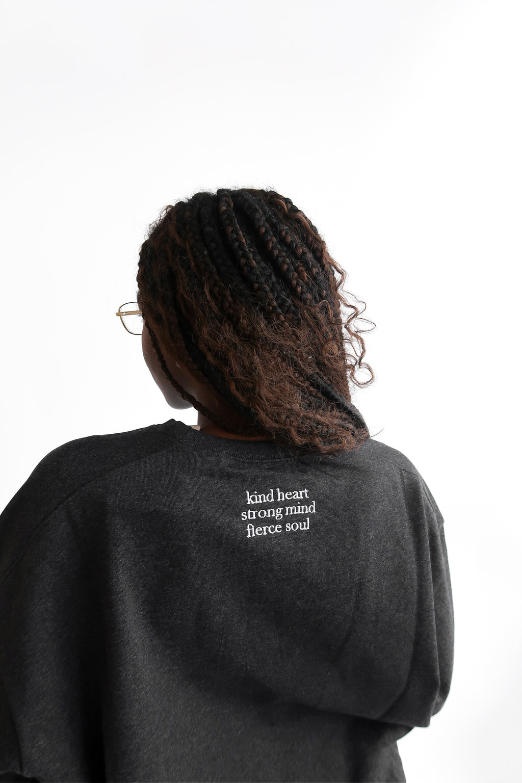 Back close up view of Erin sweatshirt in shadow reading kind heart strong mind fierce soul
