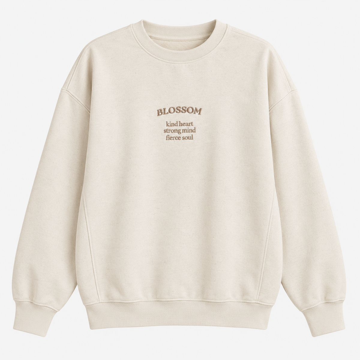 An off-white crewneck sweatshirt with 'BLOSSOM' and three lines of descriptive text 'kind heart, strong mind, fierce soul' printed in a muted brownish-gold tone on the centre chest, displayed on a clean white background.