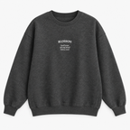 A dark gray heather crewneck sweatshirt with white text on the left chest reading 'BLOSSOM' and a smaller quote underneath that says 'kind heart, strong mind, fierce soul', displayed on a clean white background.