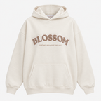 An off-white hooded sweatshirt with 'BLOSSOM' and a smaller quote printed in brown across the chest, displayed on a clean white background.